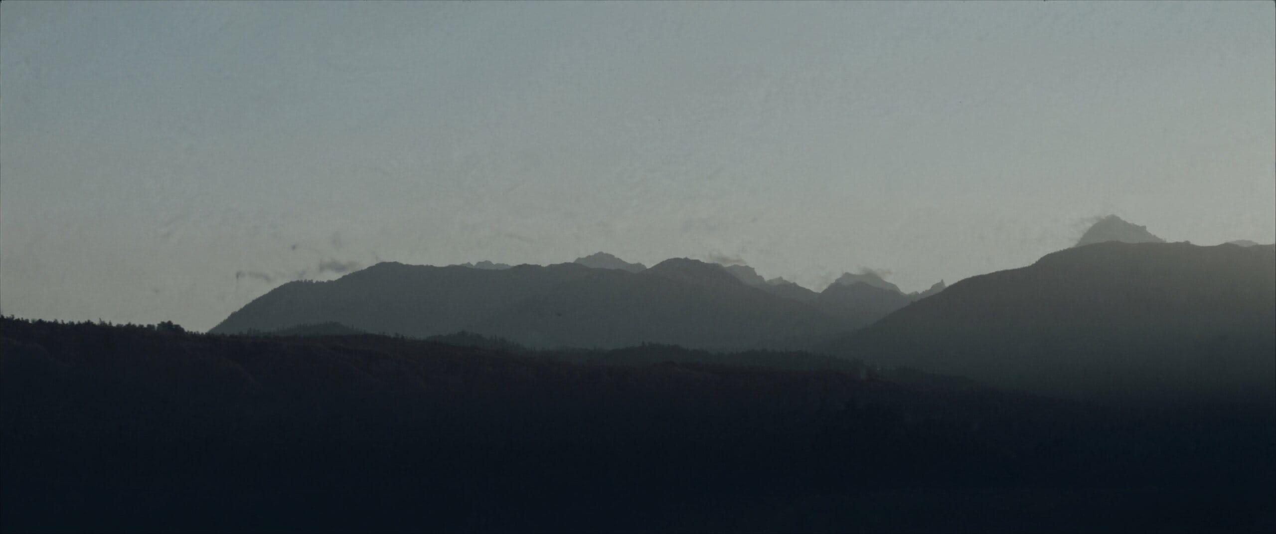 Layered Western ridgelines receding into haze at dusk.